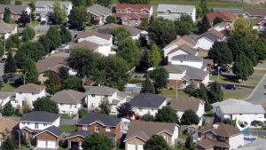 Aerial view of a suburban neighbourhood in Kingston, Ontario, showing rows of detached homes with trees, backyards, and quiet residential streets