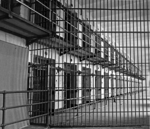 Black-and-white photo of barred walkways and rows of cells inside Kingston Penitentiary’s old wing, taken in April 1981.