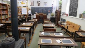 Historic classroom at the Frontenac County Schools Museum in Kingston, Ontario, featuring wooden desks, slate boards, and a teacher’s desk at the front.
