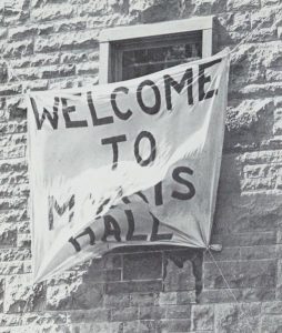 Cloth banner reading “Welcome to Morris Hall” hanging from a stone residence window at Queen’s University.
