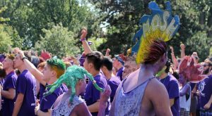 t: Queen’s University students in purple shirts and body paint celebrating Frosh Week with costumes and dyed hair.