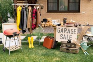 Clothing, books, toys, and household items arranged at a garage sale in Kingston, branded for Century 21 Lanthorn Real Estate