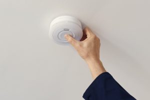 Bill Stevenson REALTOR® Kingston — homeowner testing a smoke detector during autumn to winter home preparation