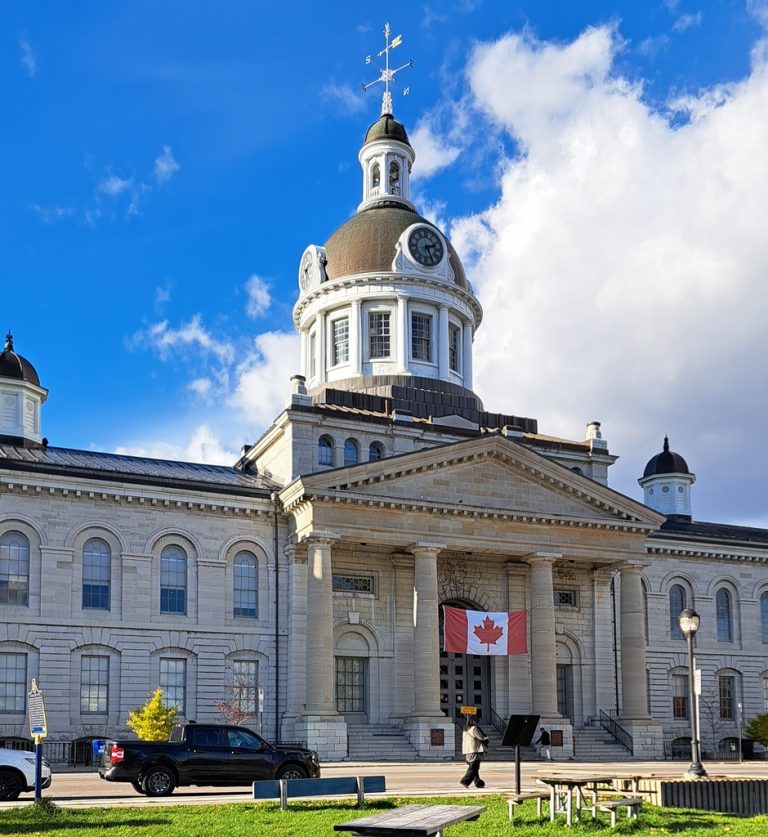Kingston City Hall on a clear day with people walking nearby, representing life in downtown Kingston.