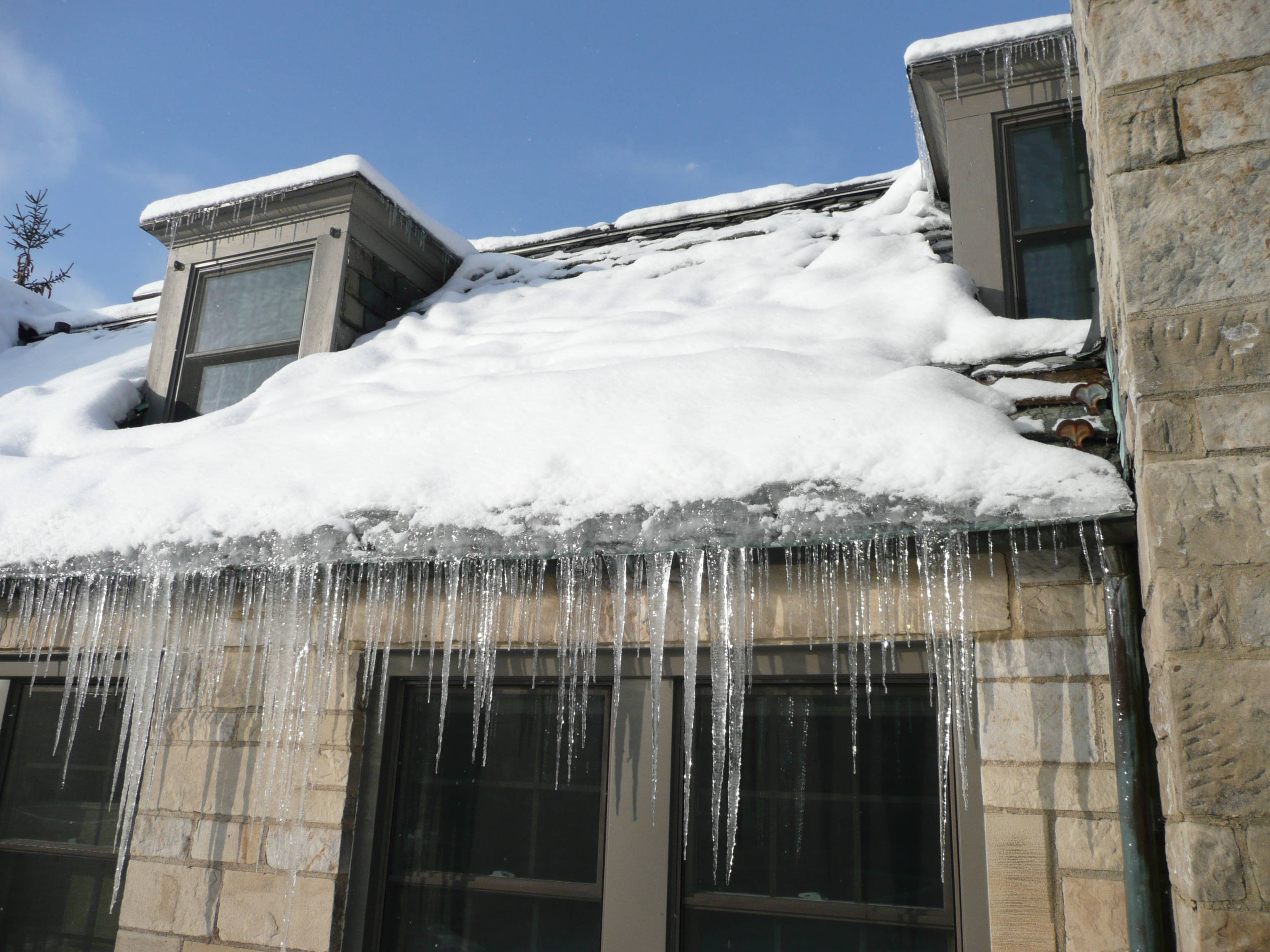 Ice dam forming along the roof edge of a Kingston and Area home, often linked to heat loss and inadequate attic insulation.