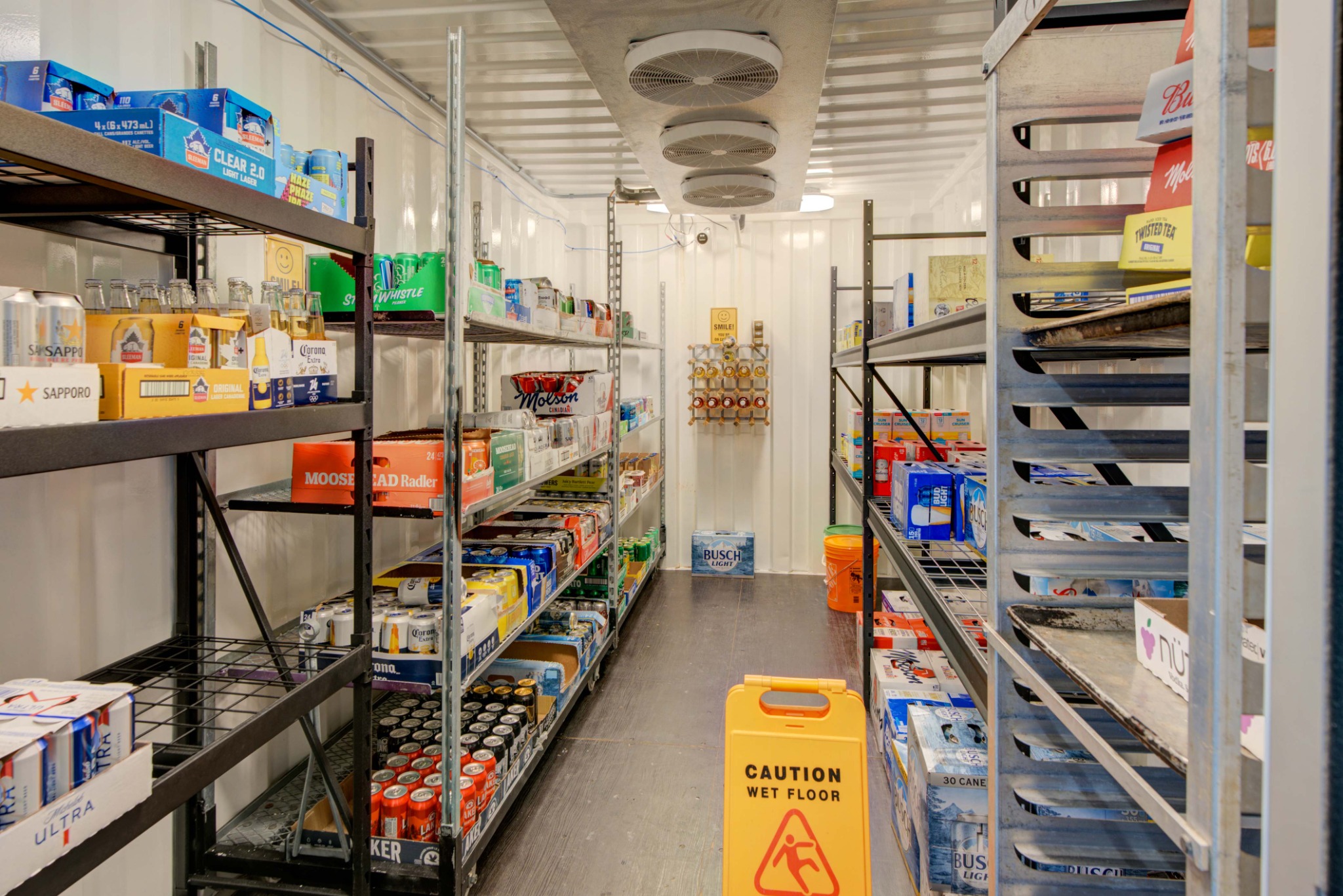 Beer cooler and beverage storage area at Chit Chat Convenience and Pizzeria in Lyn Ontario featuring refrigerated storage and shelving