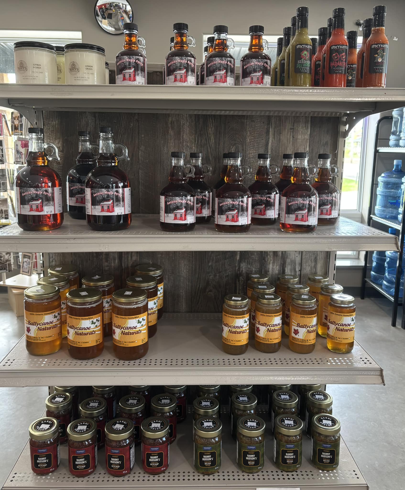 Display of local honey, jams, maple syrup, hot sauces, and specialty food products at Chit Chat Convenience and Pizzeria in Lyn Ontario.