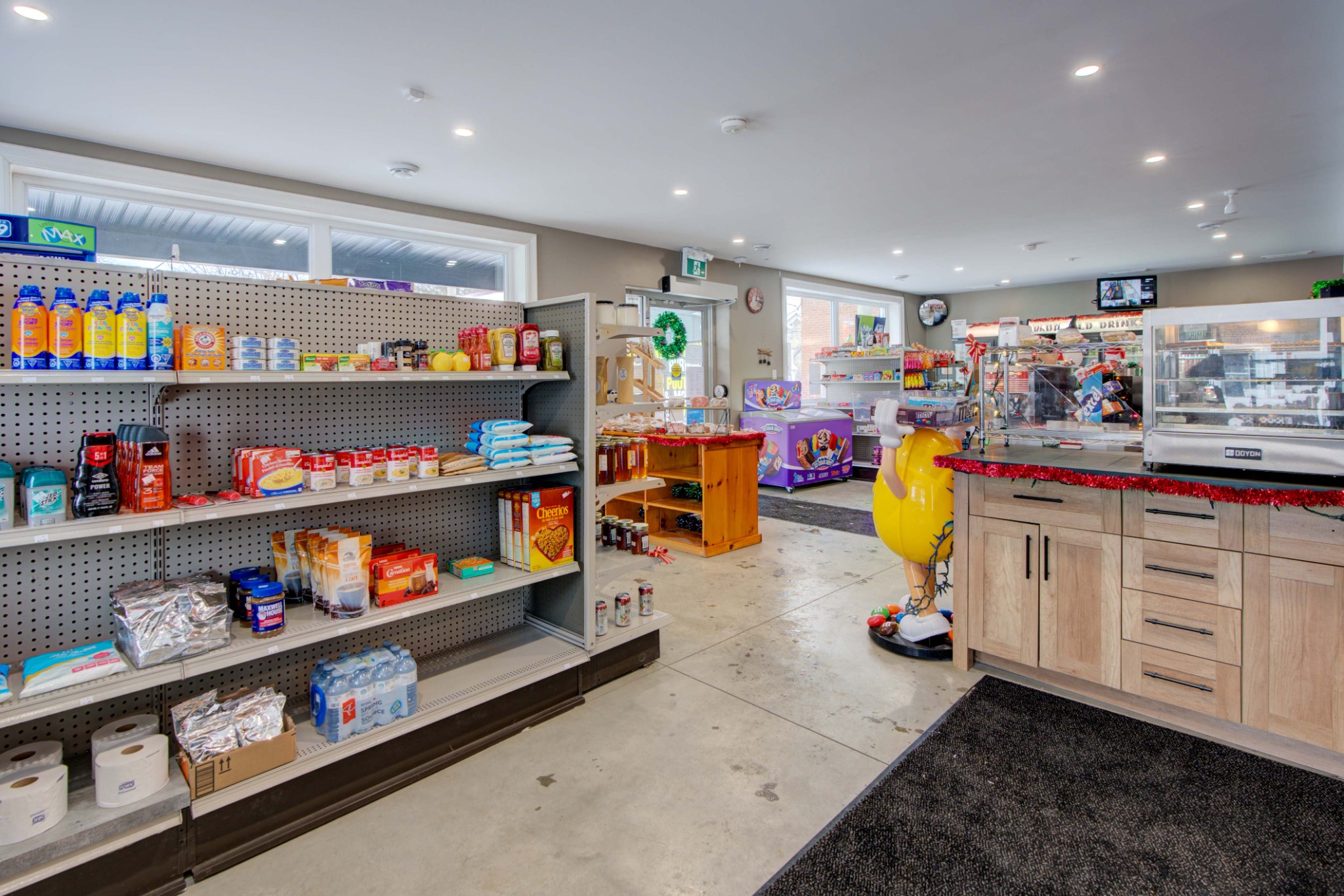 Interior of modern convenience store and takeout business featuring retail shelving, local products, desserts, and food service area.