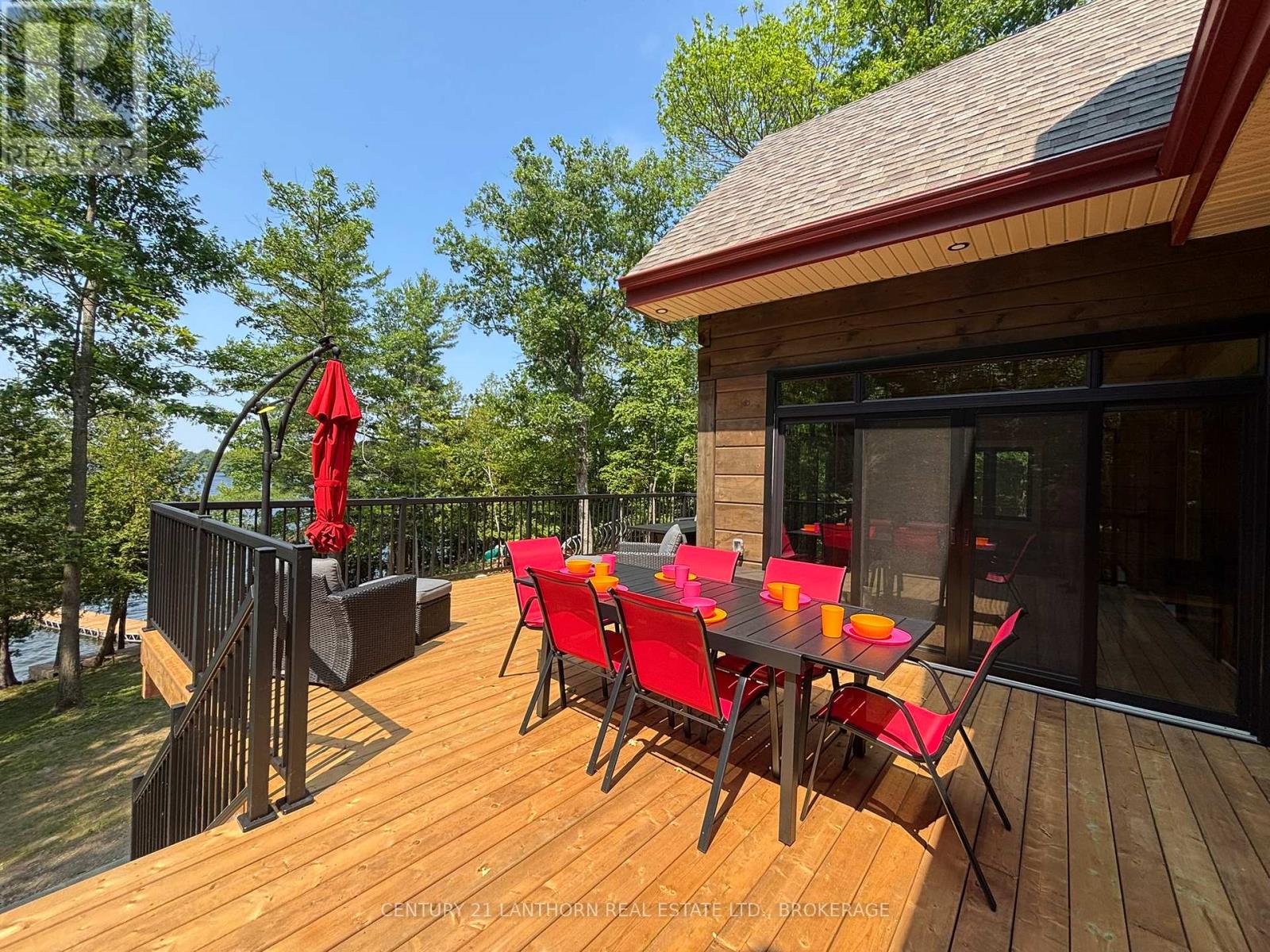 Large waterfront deck overlooking Sharbot Lake with outdoor dining area and renovated log home exterior