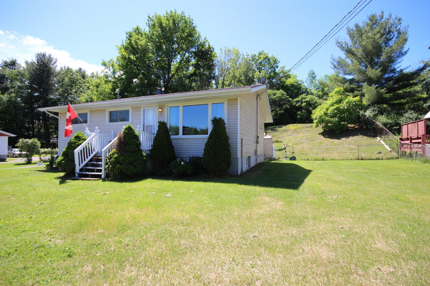 Moving to a small town near Kingston, detached home in Verona Ontario with a large yard and mature trees illustrating small-town and rural living. Bill Stevenson, REALTOR®, Century 21 Lanthorn Real Estate Ltd., Brokerage.