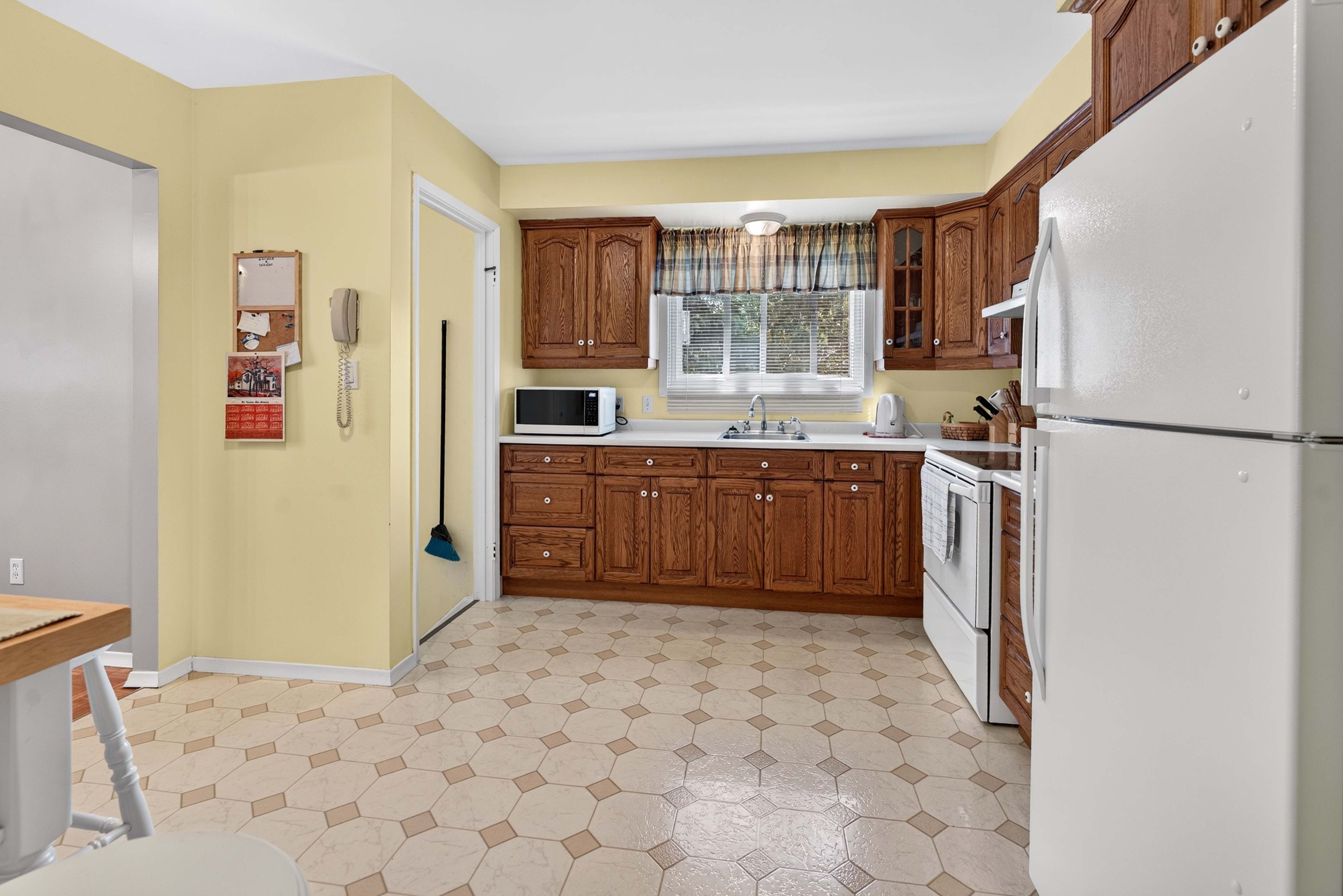 Kitchen at 742 Laidlaw Crescent Kingston with wood cabinetry, window over the sink, and included fridge and stove