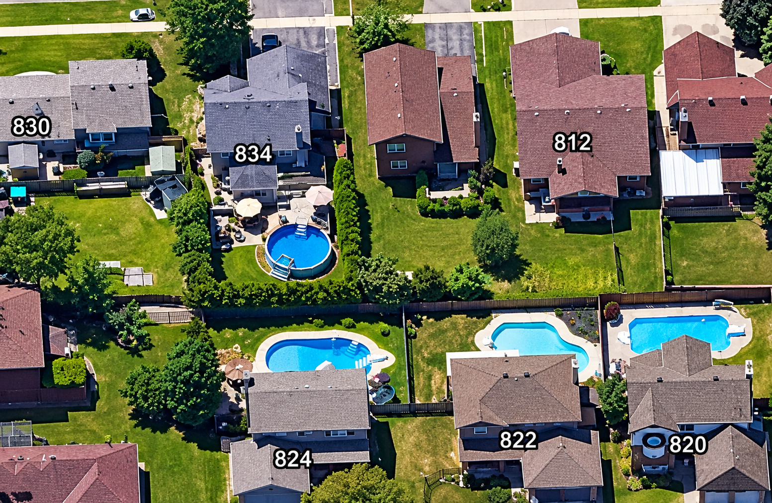 Aerial view showing several homes with swimming pools and different backyard layouts