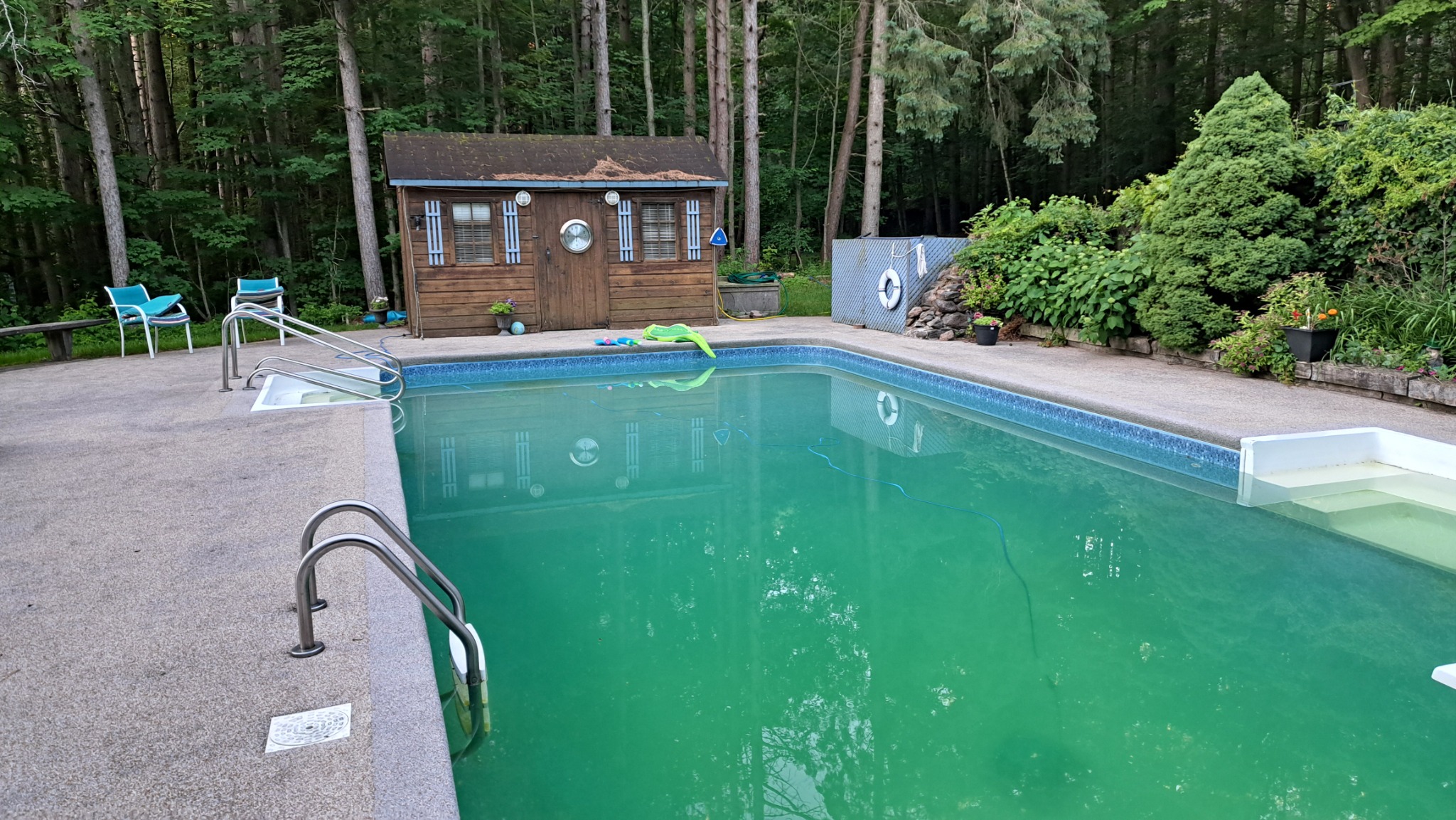 House with a pool featuring an in-ground swimming pool, pool house, patio, and wooded backyard